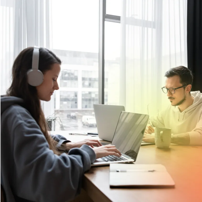 Two people working together on laptops being productive